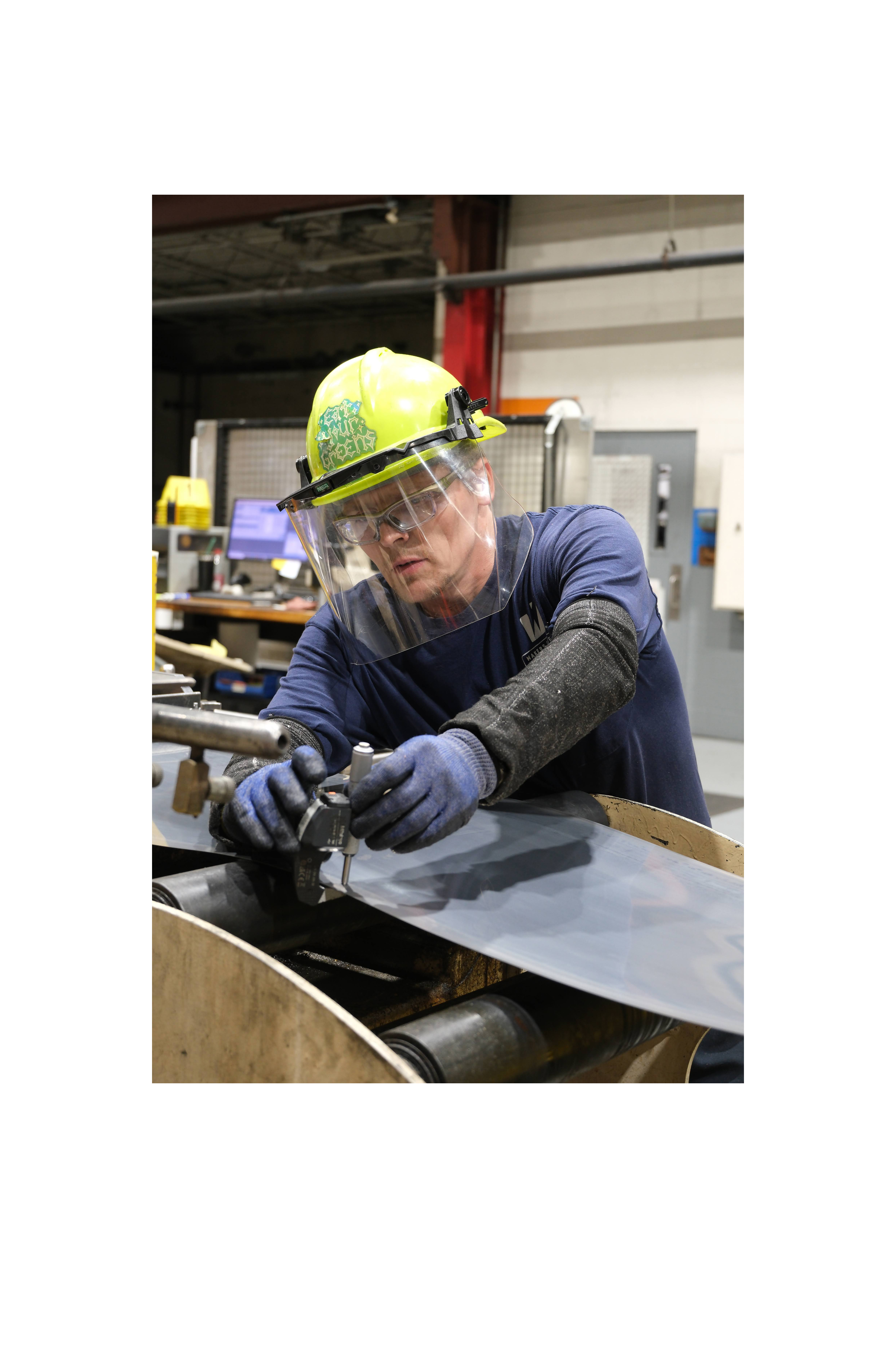 A Worthington Steel employee using a gauge in a steel processing facility.