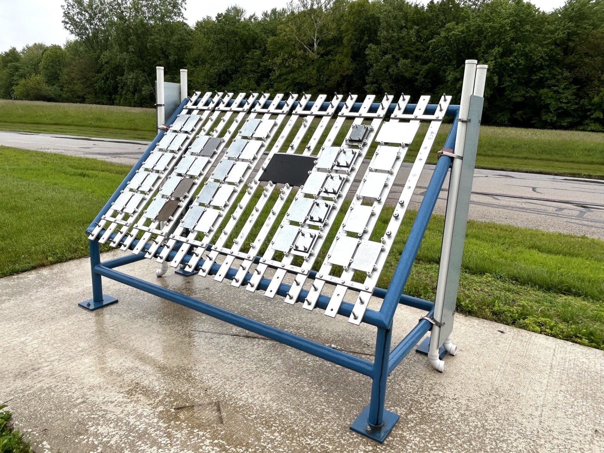 A side shot of the outdoor testing station of the coated samples in the rain.