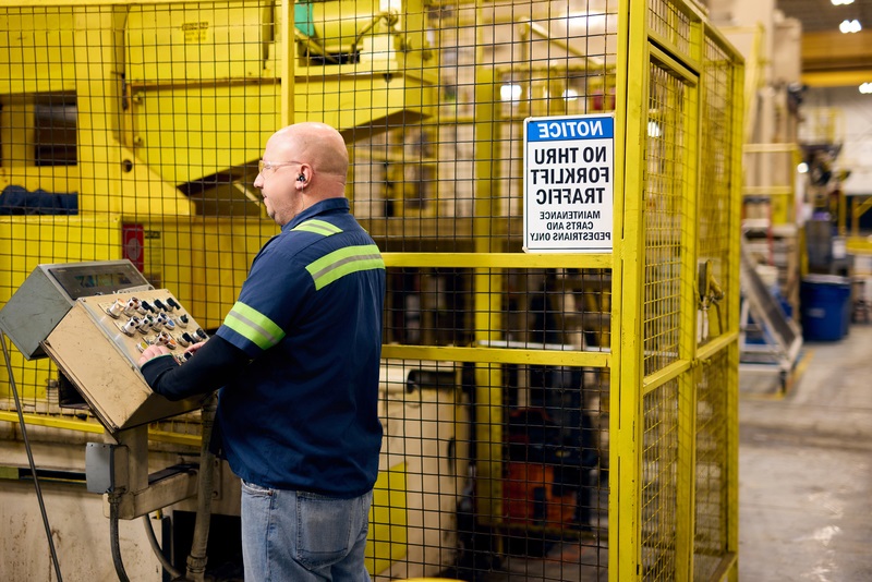 A Worthington Steel employee standing in front of a control panel inside a facility.