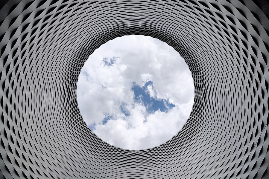 Upward view through a circular steel architectural structure with an open sky above, symbolizing Worthington Steel's commitment to sustainability.