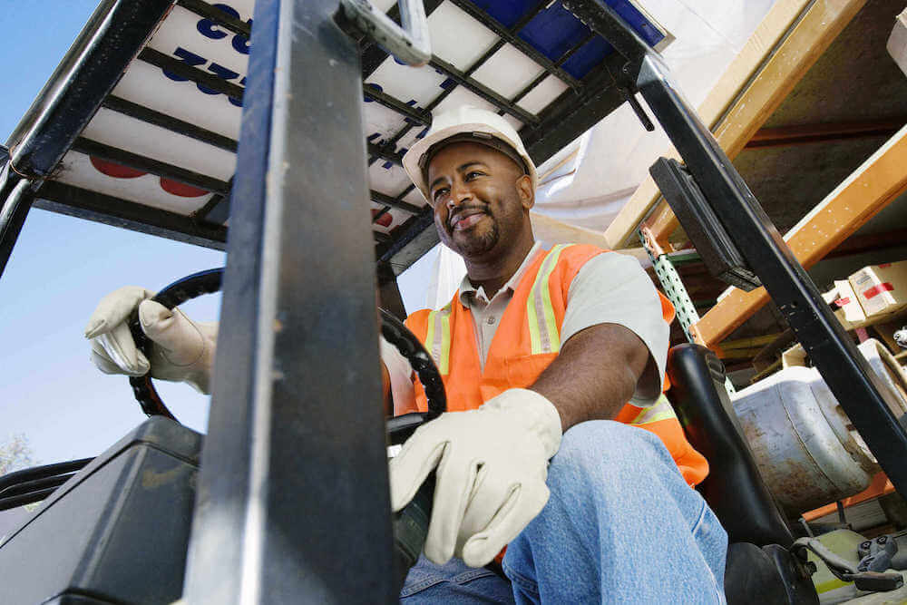 Stock photo of an employee on a forklift in a manufacturing facility.