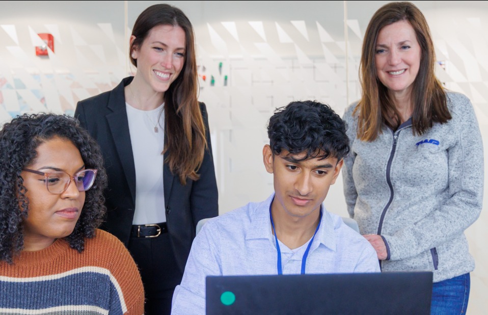 A Worthington Steel intern receiving mentorship from managers in a modern office setting.
