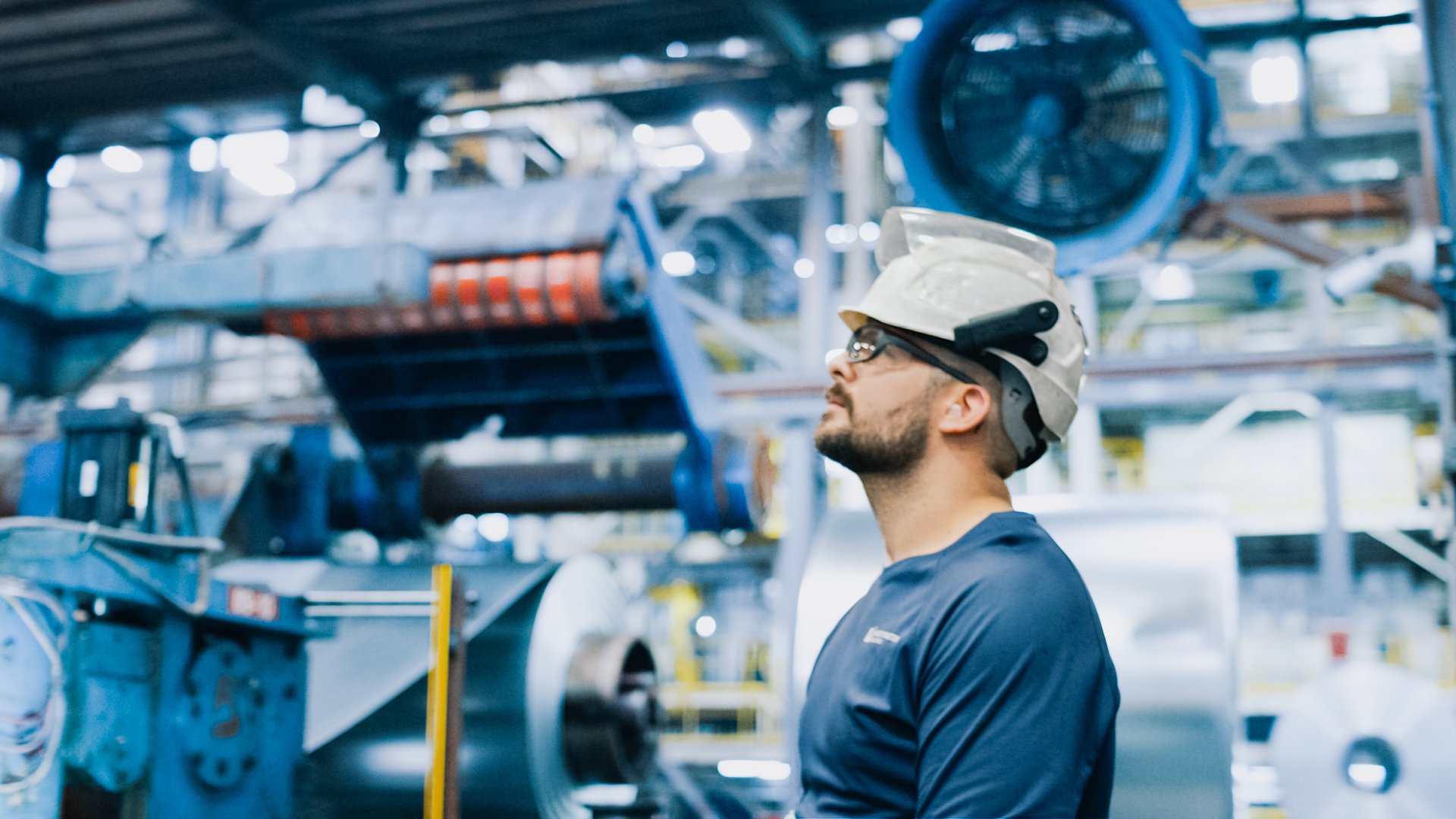 Worthington Steel team member wearing safety gear and inspecting operations inside a steel processing facility.