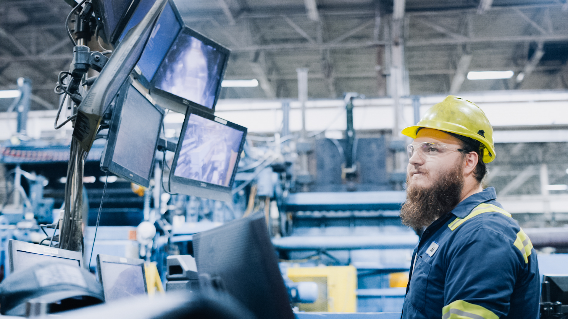 Worthington Steel employee looking up at screens in a steel processing facility.